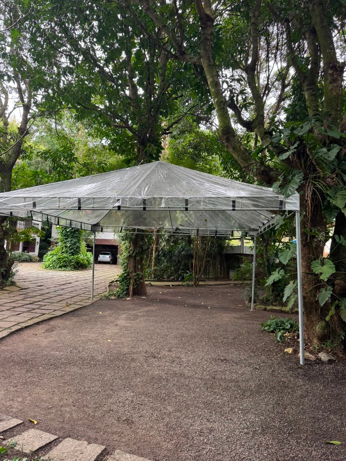 Tenda piramidal transparente montada em jardim arborizado